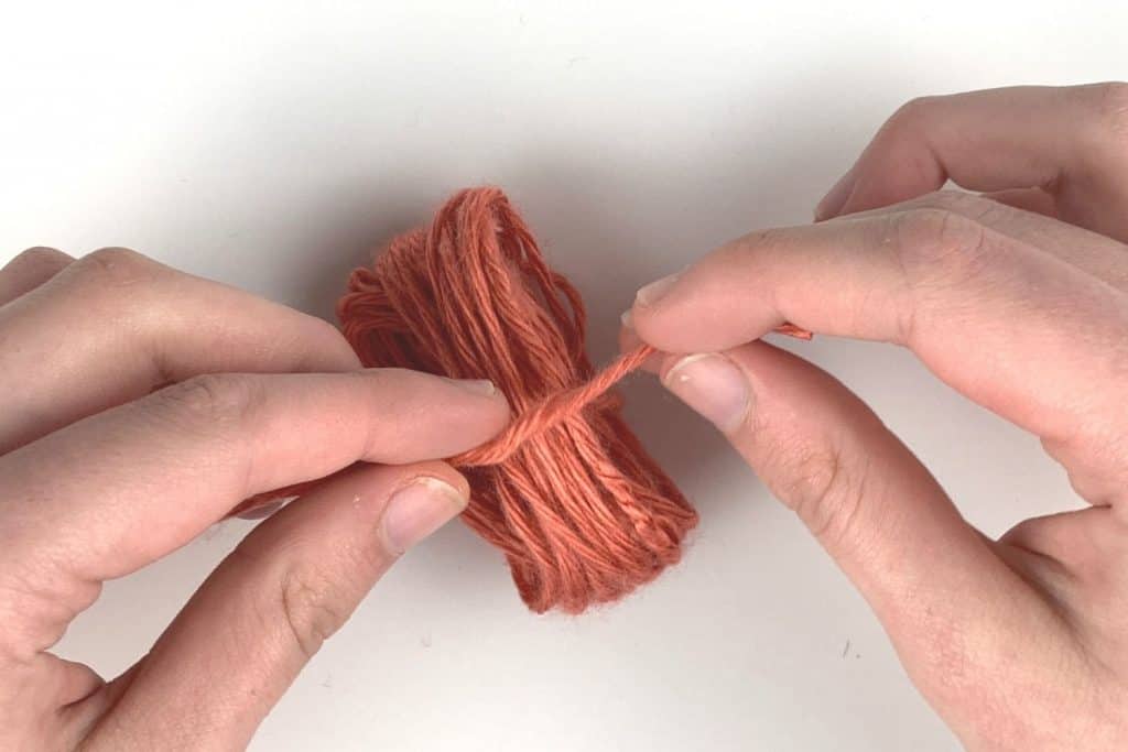 Tie off the yarn to create the pom pom shape