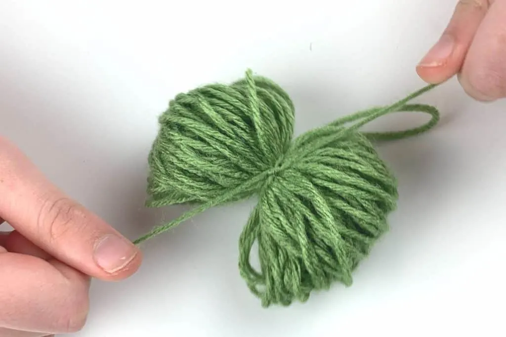 Tighten the yarn around the yarn bundle to create the pom pom
