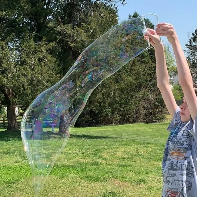 boy making a giant bubble with DIY bubble solution