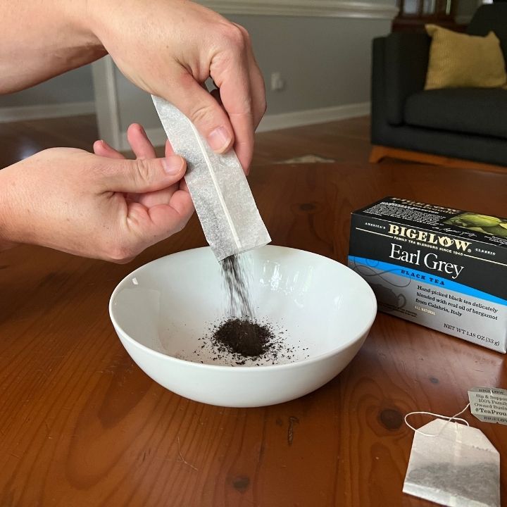 dumping the tea out of the tea bag into a bowl