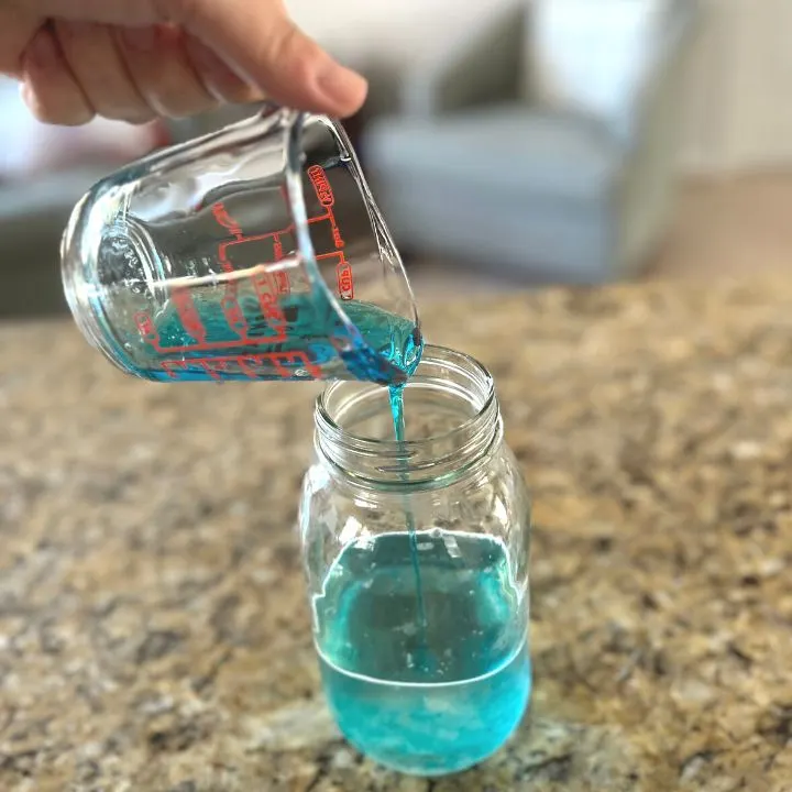 A hand pouring dish soap into a jar to make Dawn Powerwash
