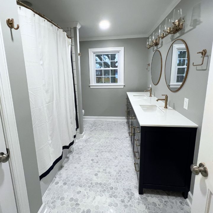 Gray bathroom with navy blue vanity and champagne bronze fixtures